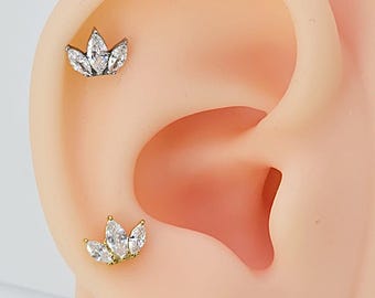 May include: Two gold ear cartilage earrings with a cluster of marquise-shaped clear stones in a flower design.