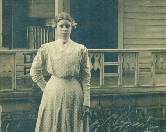 Jeune femme debout, coussin de broderie sur une chaise à l'extérieur d'une maison de ferme, véritable carte postale photo antique RPPC