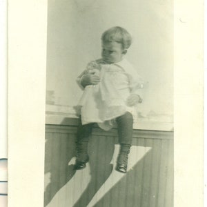 Bambino arroccato che tiene la bambola Hug Look 1910s RPPC Real Photo Postcard Foto Nero Bianco Foto