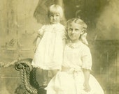 Blonde Sisters White Dress Toddler Standing on Wicker Chair 1910s RPPC Real Photo Postcard Photograph Black White Photo