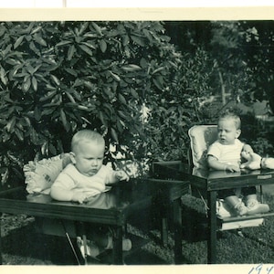 Twin Baby Boys bereit, hohe Stühle Hund Spielzeug außerhalb der 1940er Jahre Foto Vintage schwarz weiß Foto Bild essen