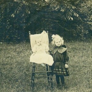 Grande soeur non impressionnée avec le bébé dans la présidence restant à l’extérieur des années 1910 RPPC Real Photo Postcard Photograph
