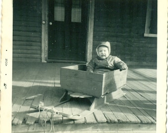 1955 Waiting For Snow Baby Sitting in Sled On Wood Porch Vintage Black White Photo Photograph