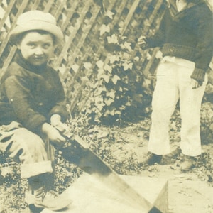 Junge Sägen durch Holz Kiste Holding Metall sägebruder beobachten 1910er Jahre Foto schwarz weiß Foto