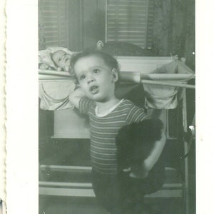 1945 Kleinkind Big Brother Looking Attention Baby Hinter halten Spielzeug 40er Jahre Vintage Foto schwarz weiß Foto