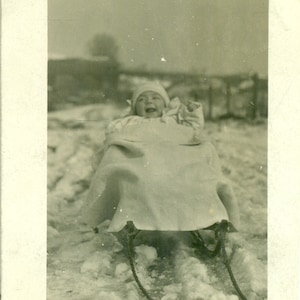 Heureux bébé assis dans une promenade en traîneau dans la neige de l'hiver Carte postale antique des années 1900 RPPC avec photo réelle