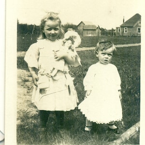 Girl Holding Doll Messy Hair Toddler Sister Standing Outside 1900s Antique RPPC Real Photo Postcard Vintage Photograph