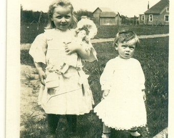 Girl Holding Doll Messy Hair Toddler Sister Standing Outside 1900s Antique RPPC Real Photo Postcard Vintage Photograph