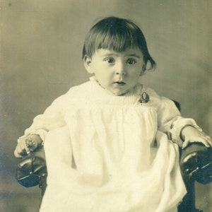驚いた赤ちゃんが大きな茶色の目をして座っているアンティーク RPPC 実写ポストカード ビンテージ写真