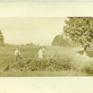 枯れ木と丸太のブラシの山で遊ぶ農場の子供たち 畑のオーバーオールの男の子 RPPC 実写ポストカード アンティーク写真 白黒写真