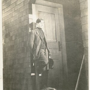 Antico uomo dell'Alaska in piedi con la cuccia per cani da slitta Malamute, veranda, cartolina fotografica reale RPPC AZO