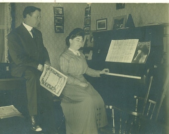 Jouant l’homme assis de Piano femme tenant musique livre salon CPPR Antique photographie Vintage carte postale