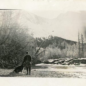 Vintage Alaska Uomo in piedi con grande cane da slitta Riva del fiume Inizio primavera RPPC Foto reale Cartolina antica