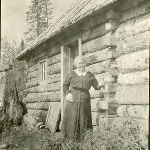 Vintage femme d'Alaska debout à côté d'une cabane en rondins d'été antique RPPC carte postale photo réelle alaska