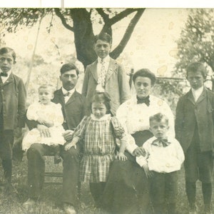 Familie mit 6 Kindern Mädchen mit Hand auf jedem Eltern Knie 1910er RPPC Echt Foto Postkarte Fotografie Schwarz Weiß Foto