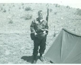 1962 Army Soldier Holding Helmet Gun Smoking by Tent Fort Carson Colorado Infantry Man Black White Photo Photograph