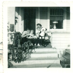 Familia jugando con juguetes mamá papá bebé niña panda oso 1950s foto negro blanco fotografía