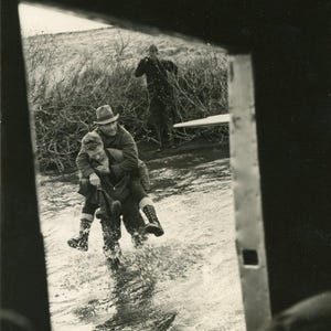 Piloto de hidroavião antigo do Alasca carregando passageiro pela água até a porta para que ele não se molhe Foto Fotografia em preto e branco