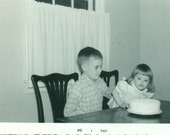 Happy Second Birthday Little Girl Blowing Out Candles on Cake With Brother 1964 Vintage Black White Photo Photograph