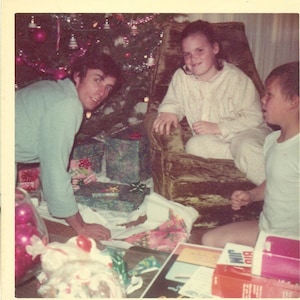 Natale mattina 1973 papà distribuendo regali bambini PJs regali albero 70s Vintage fotografia colore foto