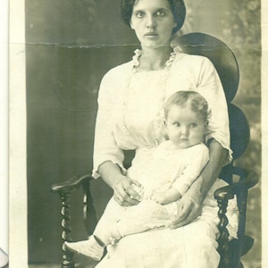 Sehr müde Mutter hält Baby mit großen Augen im Holzstuhl 1910er Jahre Antike RPPC Echtfoto-Postkarte