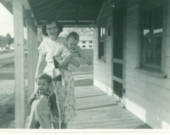 1954 Woman Standing on Front Porch Holding Baby Little Toddler Farm Boy Overalls   Vintage Photo Black and White Photograph