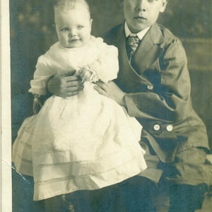 Carte postale avec photo réelle Oncle Earl Lincoln incertain tenant son bébé Jean Wilson en studio portrait antique RPPC