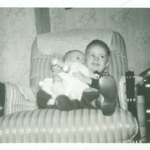 Big Brother Holding Baby Sitting in Chair With Rattle Smile 1940s Vintage Black and White Photo Photograph