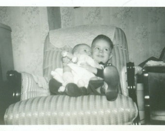 Big Brother Holding Baby Sitting in Chair With Rattle Smile 1940s Vintage Black and White Photo Photograph