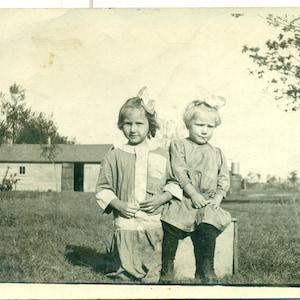 Petites filles de ferme assises sur une caisse à l'extérieur des années 1900 Antique RPPC Real Photo Carte postale