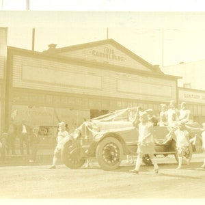 1920 Anchorage Alaska Downtown Parade Flappers Car Carrol Bldg Negozio di alimentari sanitario Fotografia antica d'epoca