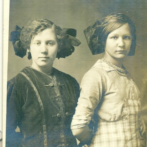 Teen Sisters Debout Robe En Velours Robe À Carreaux Nœuds Pour Les Cheveux Studio Portrait Antique RPPC Vraie Carte Postale Photo