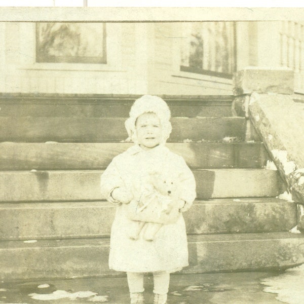 Niña de la década de 1920 sosteniendo un oso de peluche en vestido fuera del invierno RPPC Fotografía de postal de foto real Blanco negro