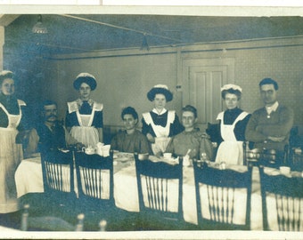 Les servantes du personnel en uniforme se tenant autour d'une table de famille Vraie carte postale photo antique RPPC