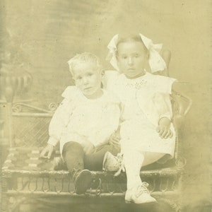 Irmã mais velha reconfortante tímido irmãozinho cadeira pernas cruzadas retrato 1910s rpc foto real cartão postal fotografia antiga