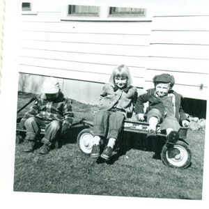 1950er Jahre Kinder sitzen in roten Wagen Bruder Sulking in kleineren ein Foto schwarz weiß Foto
