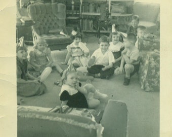 Feliz 4º cumpleaños Niños sentados en sombreros de fiesta en el piso de la sala de estar Jugando juegos Vintage 1950 Blanco y negro Fotografía fotográfica
