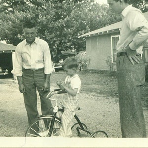 1930s Boy Riding Tricycle Men Watching Talking Striped Overalls Outside Driveway 30s Vintage Photograph Black White Photo