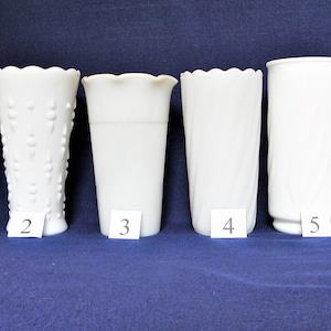 May include: Six white milk glass vases with different designs and textures. The vases are numbered 1 through 6.
