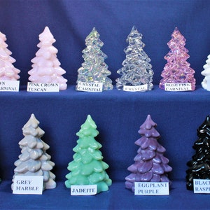May include: Ten glass Christmas tree ornaments in various colors, including pink, white, clear, teal, grey, green, purple, and black. The ornaments are arranged in two rows on a blue surface. Each ornament has a label with its color and name.