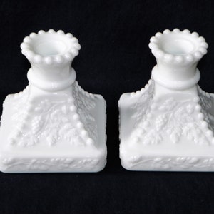 Peut inclure: Paire de bougeoirs en verre de lait blanc avec un motif de perles et un motif de vigne.