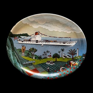 May include: A round ceramic plate with a painted scene of a ship sailing past a tropical island. The ship is white with red accents and the words "Matson" on the side. The island is green and lush with palm trees and a small village. The plate is decorated with a blue and white border.