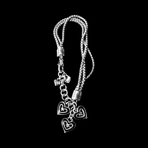 Może przedstawiać: Srebrna bransoletka z łańcuszkiem z trzema serduszkami. Serduszka są ozdobione małym k&oacute;łkiem w środku.