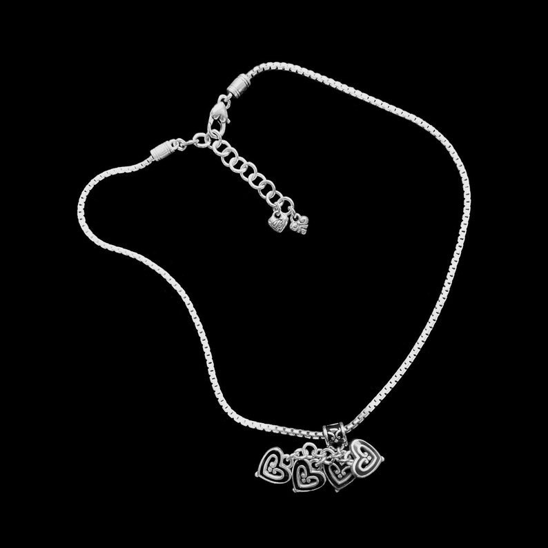 Może przedstawiać: Srebrny naszyjnik z łańcuszkiem i srebrnym zawieszką w kształcie pięciu splecionych serc. Naszyjnik zapinany jest na karabińczyk.