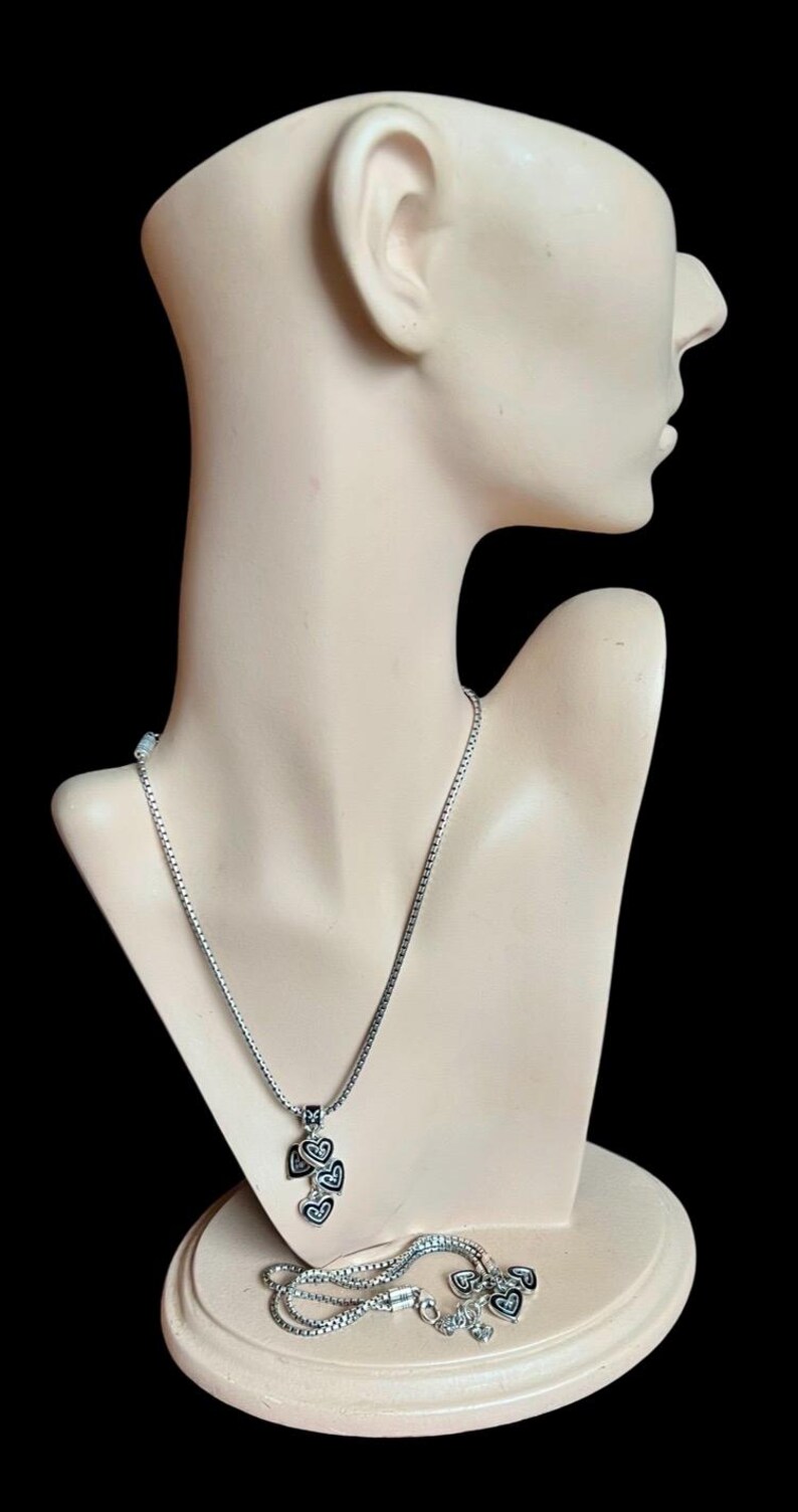 Może przedstawiać: Srebrny zestaw naszyjnika i bransoletki z zawieszką w kształcie kilku czarnych i srebrnych serc.