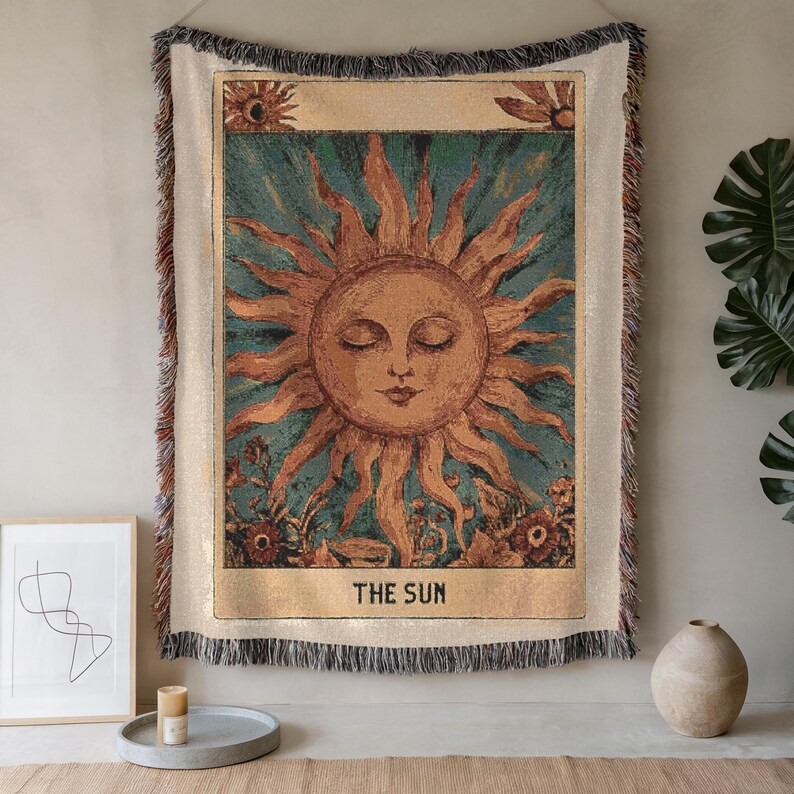 Boho woven blanket showing a tarot card in vintage style, representing "The Sun" card. Cosy throw blanket in 100% cotton, with a sunny and spiritual design in warm and natural colors. Perfect for cozy evenings at home or outdoor, available in three sizes. Must have for anyone who wants to add warm and positive decor to its home. Great gift for yourself or others.