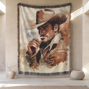 Könnte beinhalten: Ein gewebtes Wandbehang mit einem Porträt eines Mannes mit Cowboyhut, der eine Zigarette raucht. Das Kunstwerk ist in Braun-, Beige- und Beigetönen gehalten und hat einen Fransenrand. Das Bild hat eine Vintage- und rustikale Ästhetik.
