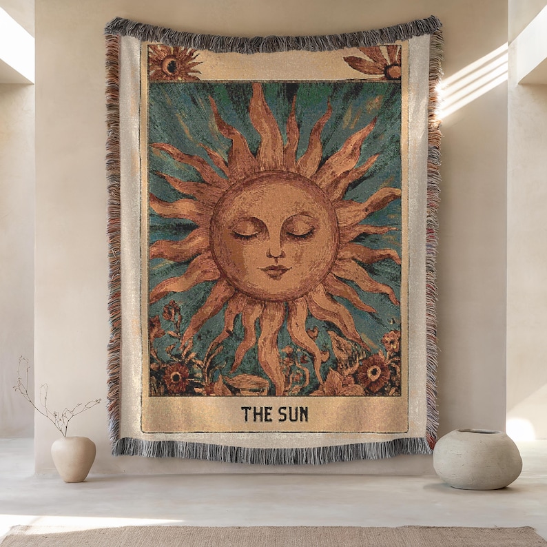 Boho woven blanket showing a tarot card in vintage style, representing "The Sun" card. Cosy throw blanket in 100% cotton, with a sunny and spiritual design in warm and natural colors. Perfect for cozy evenings at home or outdoor, available in three sizes. Must have for anyone who wants to add warm and positive decor to its home. Great gift for yourself or others.