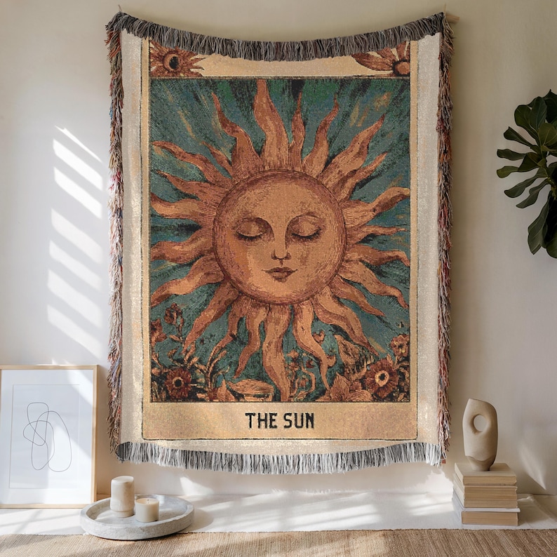 Boho woven blanket showing a tarot card in vintage style, representing "The Sun" card. Cosy throw blanket in 100% cotton, with a sunny and spiritual design in warm and natural colors. Perfect for cozy evenings at home or outdoor, available in three sizes. Must have for anyone who wants to add warm and positive decor to its home. Great gift for yourself or others.
