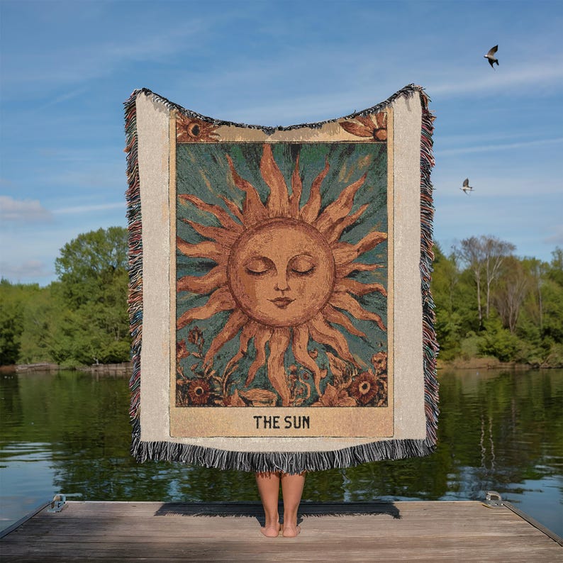 Boho woven blanket showing a tarot card in vintage style, representing "The Sun" card. Cosy throw blanket in 100% cotton, with a sunny and spiritual design in warm and natural colors. Perfect for cozy evenings at home or outdoor, available in three sizes. Must have for anyone who wants to add warm and positive decor to its home. Great gift for yourself or others.